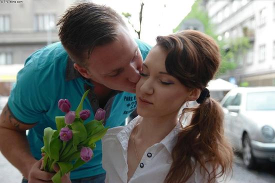 Молодой человек дарит букет цветов русской девушке и целует в щеку
